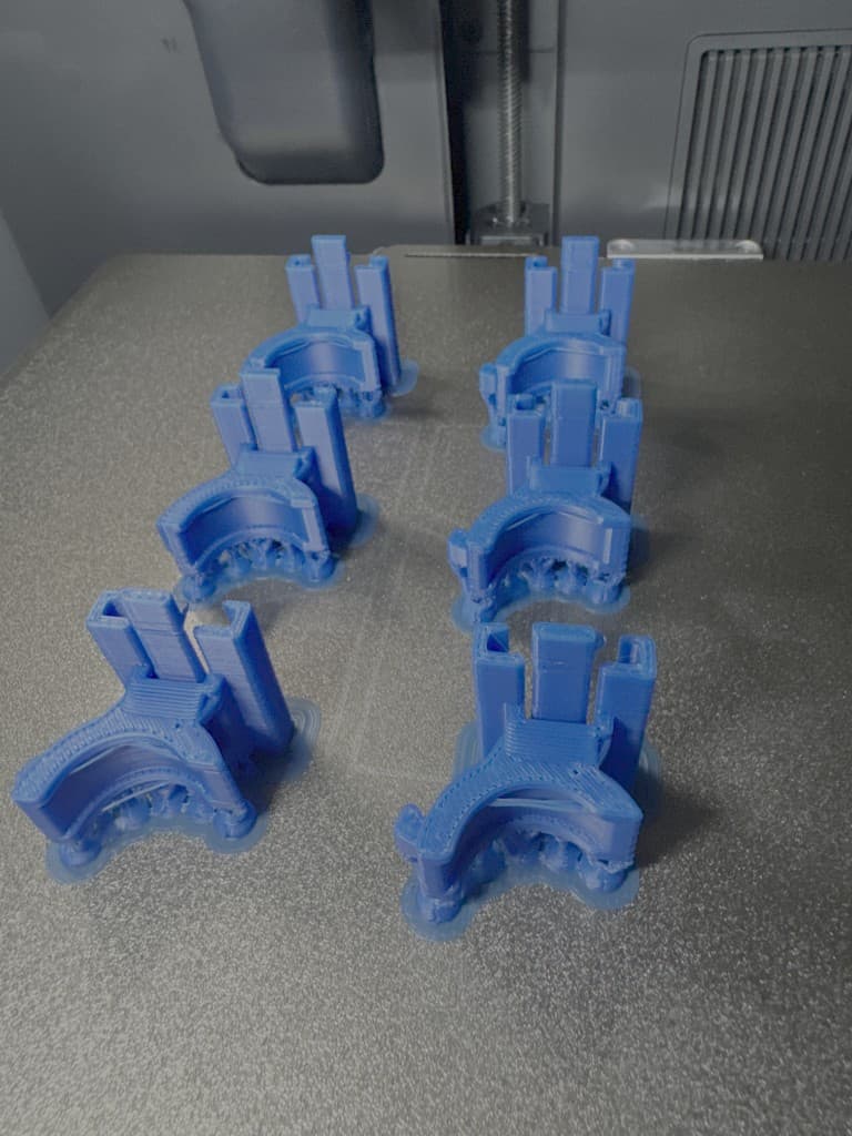 Blue BajkBuddy clamp bases arranged on a 3D printer build plate