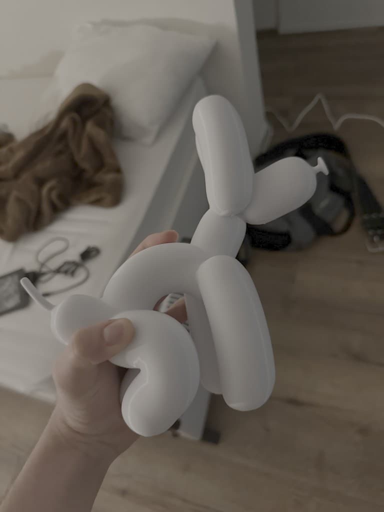 White dog-shaped BajkBuddy figurine held indoors before being attached to a bike